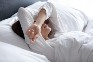 Woman waking up after bad dream, covering eyes